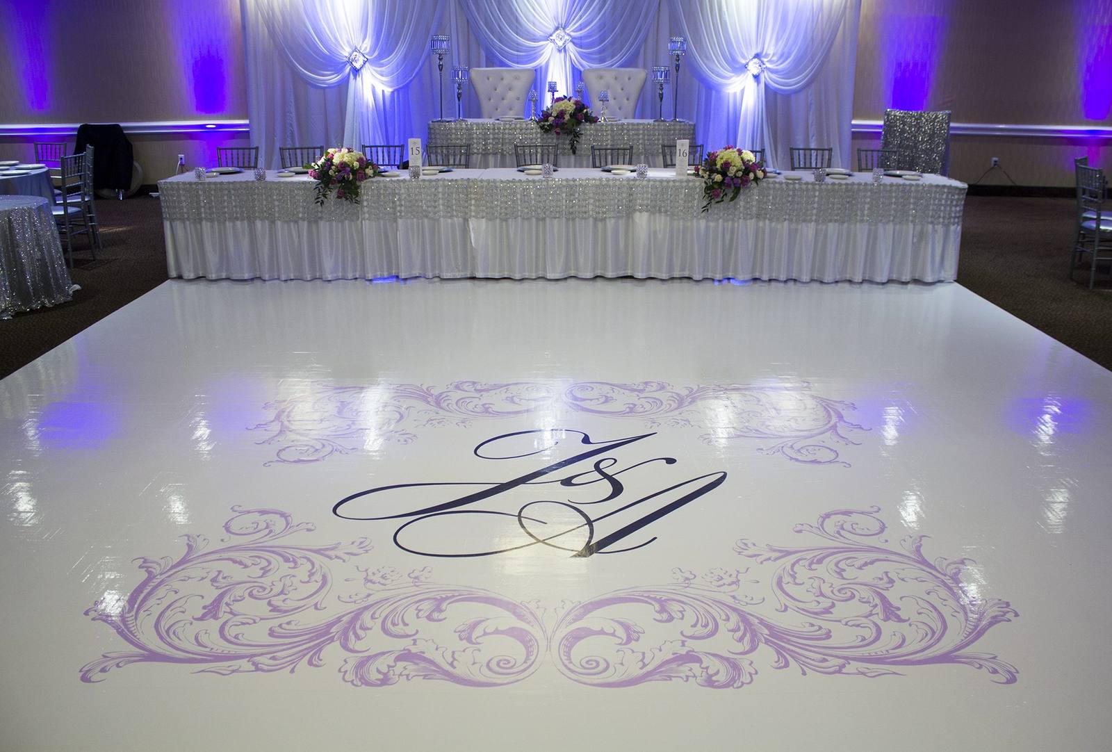 A white printed dance floor with lilac scrollwork and a navy script monogram.
