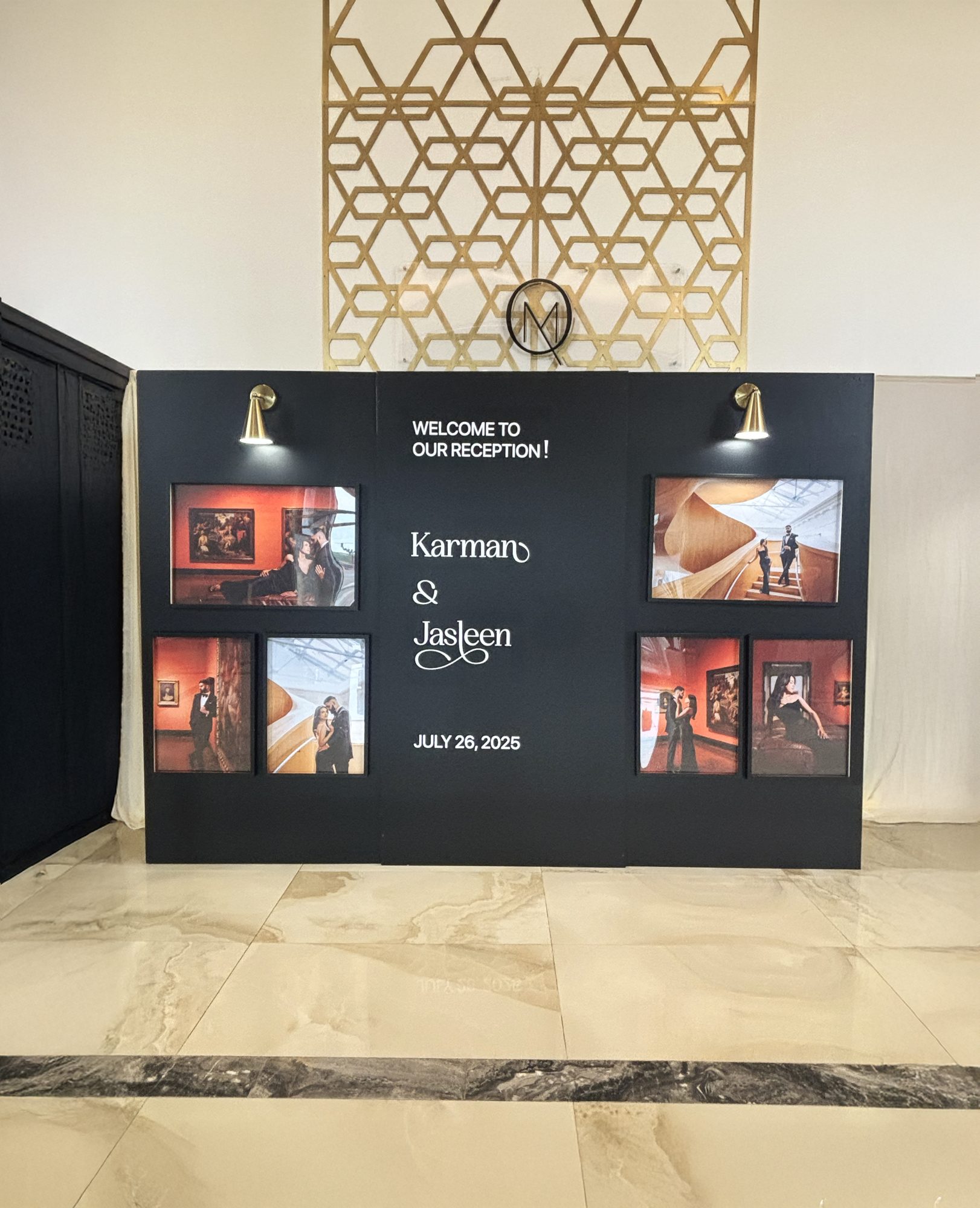A fabricated black backdrop wall at a wedding reception, with printed photographs inset into cut openings, custom lettering and mounted brass lights.