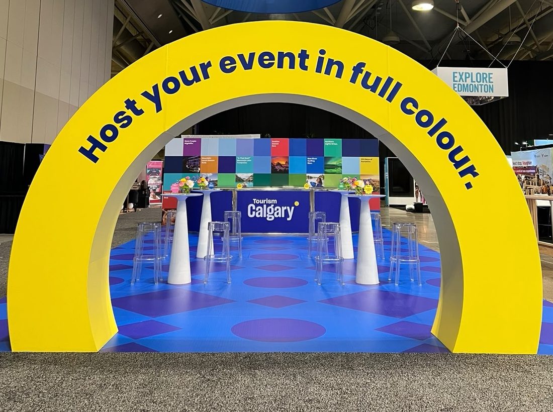A fabricated arch with printed lettering standing over a matching printed floor at an event.